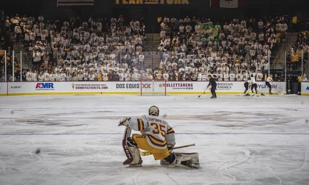 ASU hockey player in front of a packed student section at Mullet Arena.