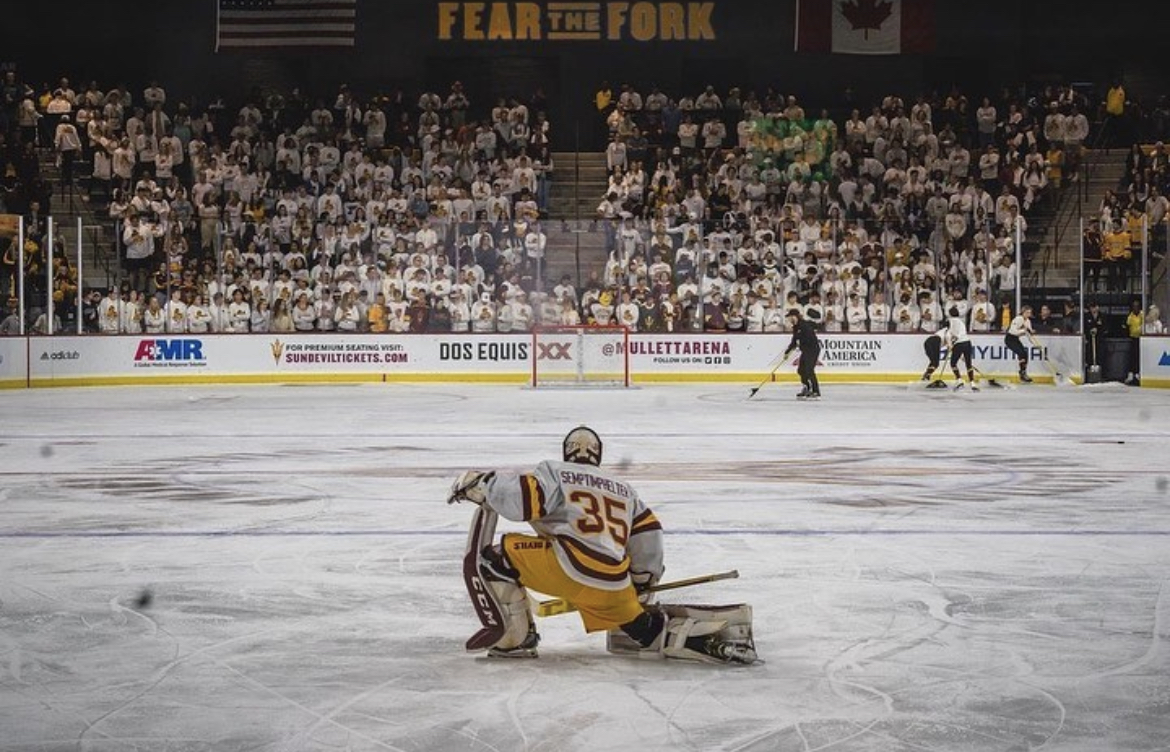 ASU hockey player in front of a packed student section at Mullet Arena.