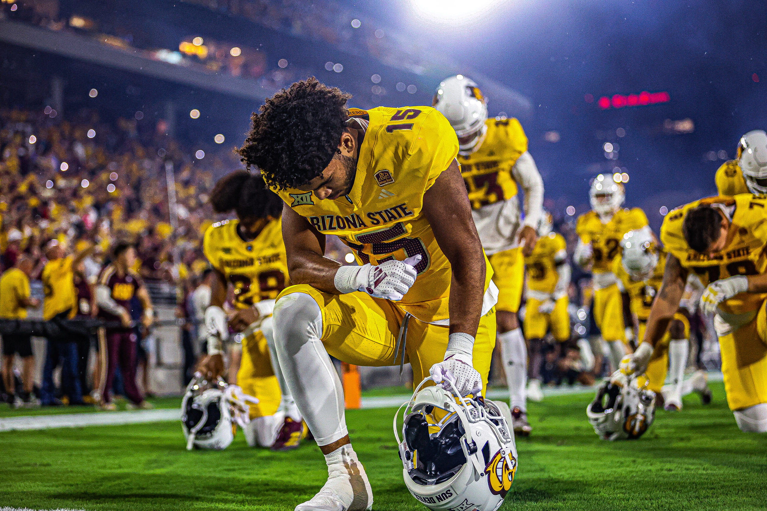 An ASU football player kneels before the Sun Devils' game against Mississippi State.