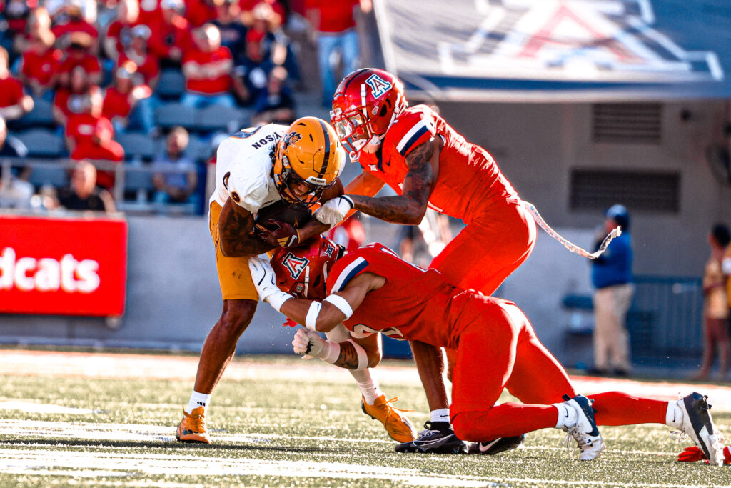 Jordyn Tyson is tackled by two Arizona defenders in the Territorial Cup on Nov. 30, 2024.